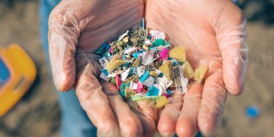 hands holding microplastics on the beach.